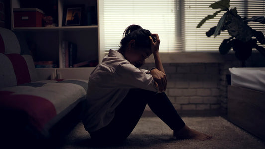 a woman in a dark room holding her head in dispair