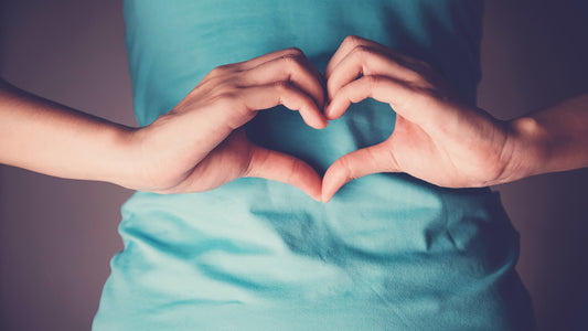 Image of a person making a heart shape with their hands over the stomach